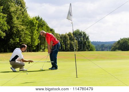 Senior man practicing golf with teacher helping