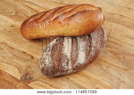 different rye and white flour french bread loaf with on light wooden table background