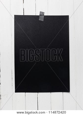 Blank Black Poster Hanging On A Tape On White Wooden Plank Wall.