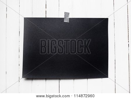 Blank Black Poster Hanging On A Tape On White Wooden Plank Wall.