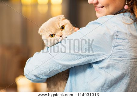 happy woman holding scottish fold cat at home