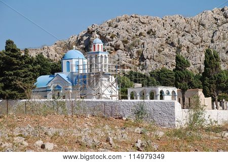 The blue domed church in the cemetery at Emborio on the Greek island of Halki. The bell tower is supported by scaffolding due to structural damage.