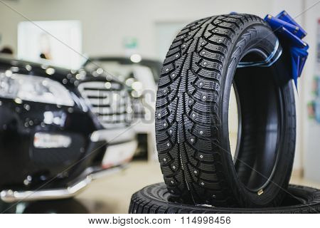 Stack of car tires in the showroom. New cars in bokeh
