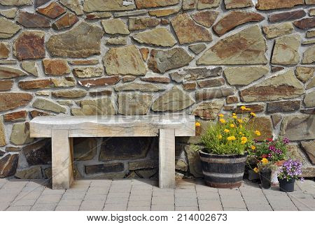 Bench seat flowers and stone wall background in Tenby Wales UK.
