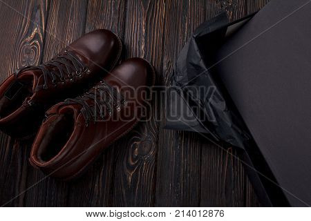 Men's lether boots on the brown wooden table overhead view. Shoe with shoe box