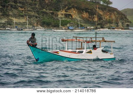 RINCA INDONESIA-MARCH 15: Unidentified men sit in traditional boat in Komodo National Park on March 152012 in Nusa Tenggara Indonesia. Most of the people in Komodo National Park make their living out of fishing