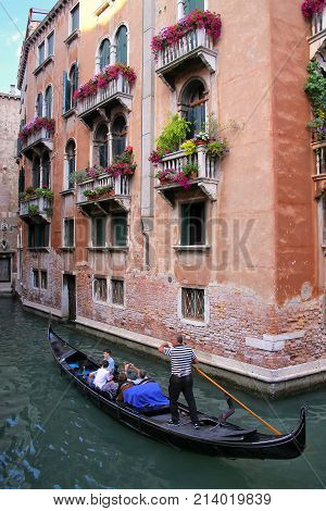 VENICE ITALY-JUNE 21: Unidentified people ride in gondola on June 21 2015 in Venice Italy. Venice is situated across a group of 117 small islands that are separated by canals and linked by bridges.