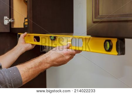 Rear View Of Serviceman Fixing Cabinet Kitchen