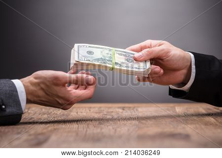 Close-up Of A Person Giving Bribe To Businessperson At Workplace