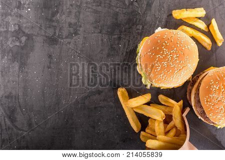 Fast food background. French fries and a burger on a stone table. Top view with copy space.