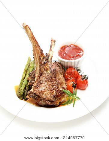 grilled lamb steak with asparagus and tomatoes on a white background