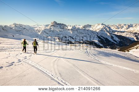 Couple hiking with snowshoes at sunset in winter mountain landscape. Alps in Germany, Bavaria, Allgau.
