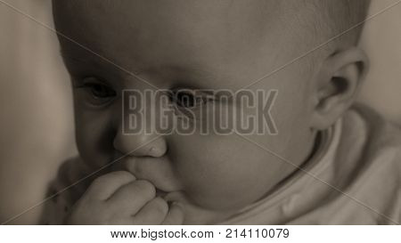 Cute baby sad and thinking hard holding her hand at the mouth and watching down