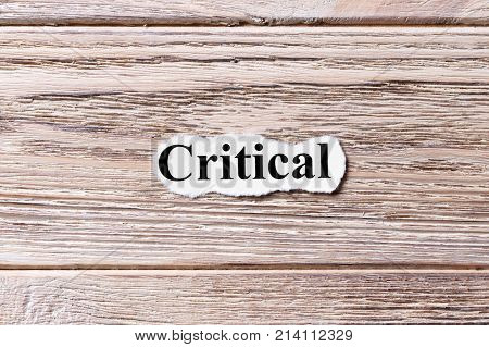 CRITICAL of the word on paper. concept. Words of CRITICAL on a wooden background.