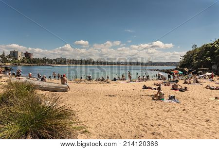 Sydney Australia - March 26 2017: Small Shelly Beach at Cabbage Tree Bay Aquatic Reserve at Manly with sand and Tasman Sea. People on the sand and in the water. White clouds in blue sky.