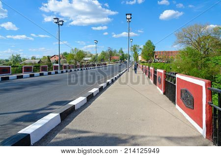 POLOTSK BELARUS - MAY 19 2017: Red Bridge over River Polota (monument of war of 1812 on Polotchyna) Polotsk Belarus. Unknown people walking down street