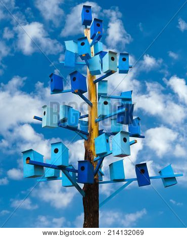 A lot of blue birdhouses on a trunk tree over sky. Clipping Path included.