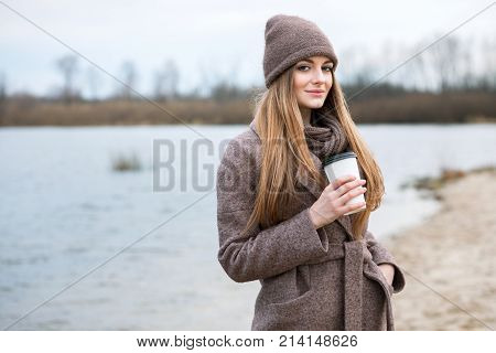 Girl In A Knitted Hat And Scarf With A Mug In The Fall On Nature