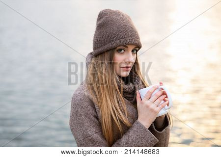 Girl In A Knitted Hat And Scarf With A Mug In The Fall On Nature