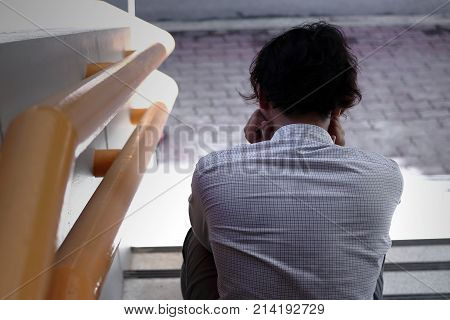 Back view of frustrated stressed young Asian business man feeling tried or exhausted at staircase of office.