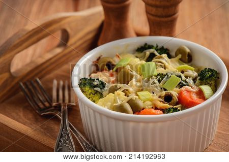 Casserole with vegetbales and cheese on wooden background..
