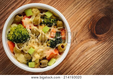 Casserole with vegetbales and cheese on wooden background..