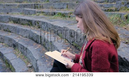 Attractive Young Female Student Preparing For Lectures In University While Sitting On The Stairs, Wr