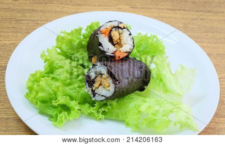 Japanese Cuisine Traditional Vagetarian Japanese Rice Maki Sushi Roll Stuff with Tofu and Carrot Wrapped in Nori Seaweed Served on Green Oak.