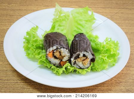 Japanese Cuisine Traditional Vagetarian Japanese Rice Maki Sushi Roll Stuff with Tofu and Carrot Wrapped in Nori Seaweed Served on Green Oak.