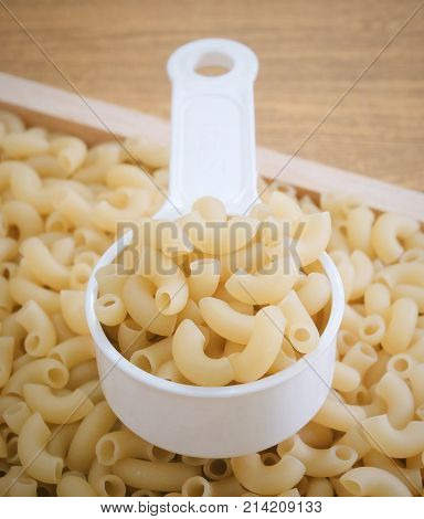 Food and Cuisine Uncooked and Dried Elbow Macaroni or Gomiti Pasta in Plastic Measuring Cup.