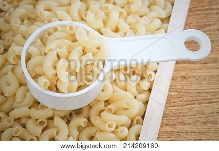 Food and Cuisine Uncooked and Dried Elbow Macaroni or Gomiti Pasta in Plastic Measuring Cup.