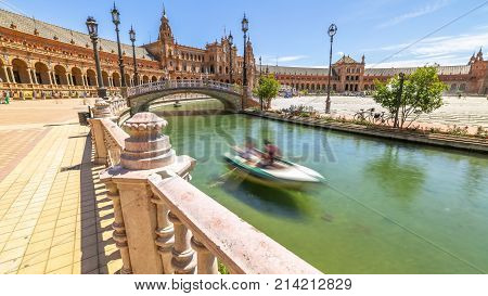 Daily boat trip at Plaza de Espana. River with boats and moving people in Seville, Andalusia, Spain