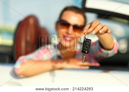 Young pretty woman sitting in a convertible car with the keys in hand - concept of buying a used car or a rental car