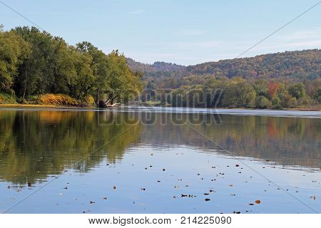 Autumn on the Susquehanna River with fall colors and leaves in the water.