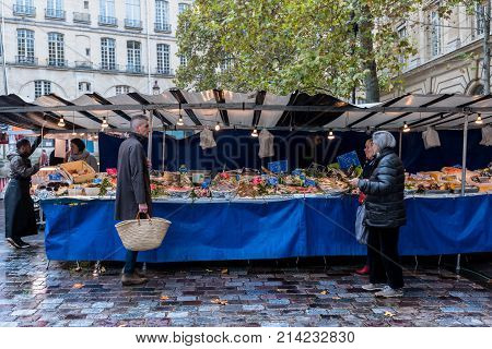 Paris France -- November 4 2017 -- Shoppers look over an outdoors Parisan fish market stand. Editorial Use Only.