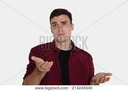 C'mon. Brunette young male in plaid shirt frowning and gesturing in indignation while convincing someone of something. Puzzled casually dressed guy shrugging shoulders having confused look