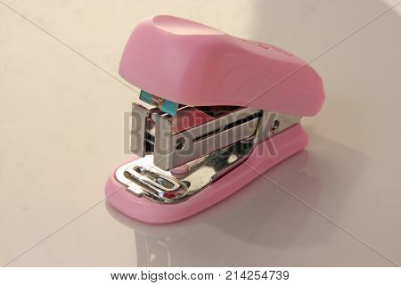 Pink colored stapler tool. Pink colored office tool.