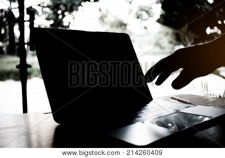 silhouette black and white of anonymous hacker typing on keyboard of laptop for remotely hacking and receiving personal information Cyber Payment Security Concept. Hacked in Black