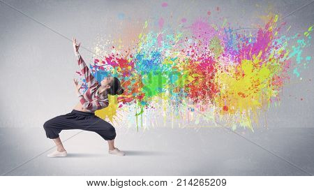 A funky contemporary hip hop dancer dancing in front of grey background with colorful bright paint splatter concept