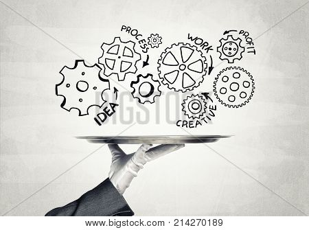 Butler holding metal tray with teamwork concept against concrete background