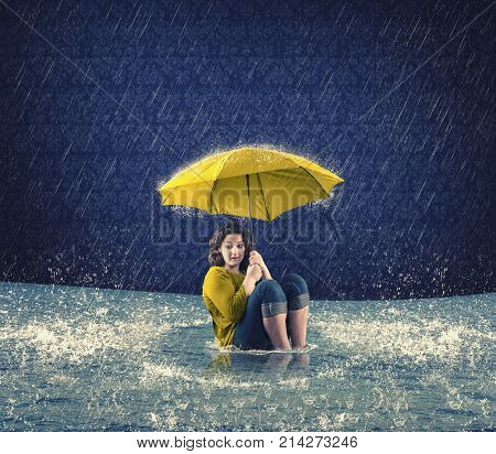 Scared woman holding an umbrella while it raining in the house and the floods came inside.