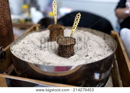 Preparing coffee in coffee jezvas in sand. Turkish method of preparing coffee. Eastern coffee.