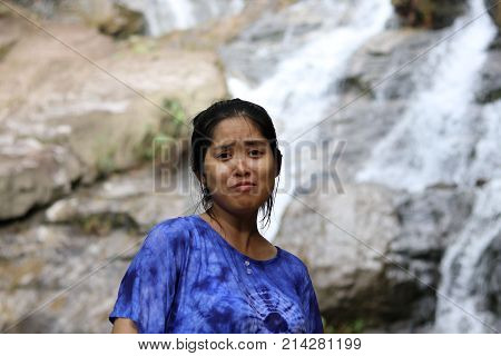Women are making funny faces And behind is the waterfall.