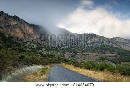 Mountain landscape with the a single lane road and cloudy sky at Pentadakiloys mountain range Cyprus