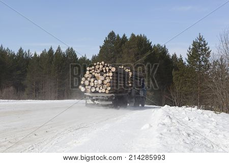 Truck laden with round logs traveling on a winter road in northern Russia