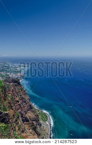 View of Atlantic ocean blue sky rocky coastline and part of Camara de Lobos town as seen from highest european cliff Cabo Girao Madeira island Portugal.