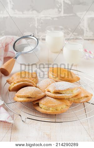 Pasties with cottage cheese and powdered sugar on a light wooden background. Traditional Russian pastry Sochnik. Selective focus. .