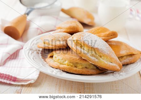 Pasties with cottage cheese and powdered sugar on a light wooden background. Traditional Russian pastry Sochnik. Selective focus. .