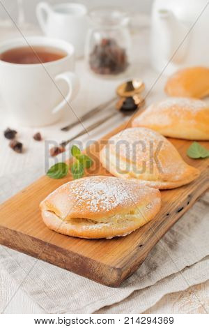 Pasties with cottage cheese and powdered sugar on a light wooden background. Traditional Russian pastry Sochnik. Selective focus. .