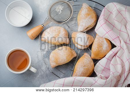 Pasties with cottage cheese and powdered sugar on a gray stone or concrete background. Traditional Russian pastry Sochnik. Selective focus. Top view.